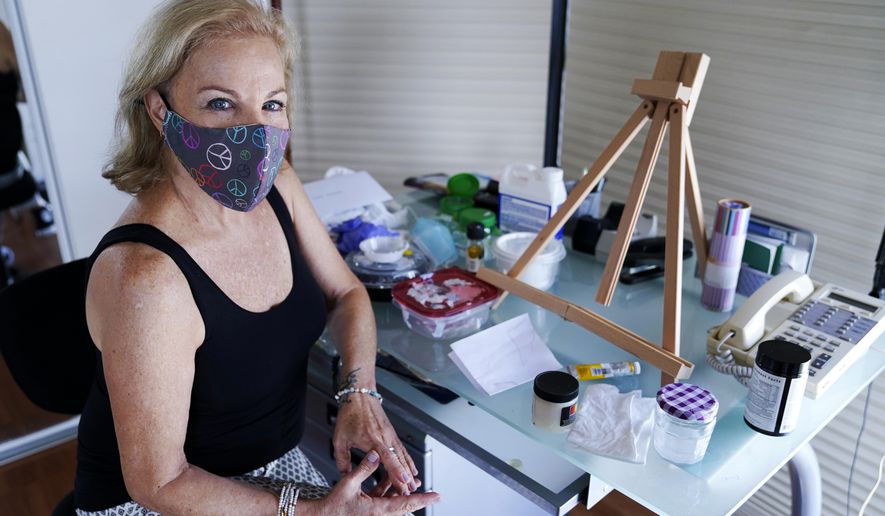 Artist Irene Pressner poses for a photograph on Aug. 21, 2020, in Aventura, Fla. The Venezuelan artist, a COVID-19 survivor who lost her husband to the virus, is creating new works inspired by her experience. (AP Photo/Lynne Sladky)