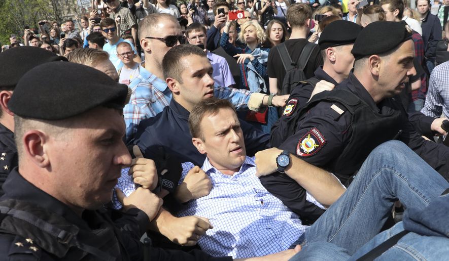 FILE - In this May 5, 2018, file photo, Russian police carry opposition leader Alexei Navalny, center, from a demonstration against President Vladimir Putin in Pushkin Square in Moscow, Russia. Attempts over the years to silence Kremlin critic Navalny have all failed so far. Now Navalny is in a coma in a Berlin hospital after suffering what German authorities say was a poisoning with a chemical nerve agent while traveling in Siberia on Aug. 20. (AP Photo, File)
