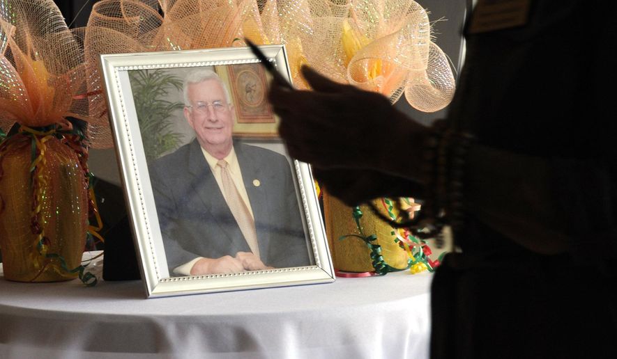 A person entering a memorial service for Mayor Billy Joe Driver in Clanton, Ala., walks past a photo of the longtime public official on Friday, Aug. 28, 2020. Driver's death of COVID-19 shocked the central Alabama community, where residents say many people thought the illness caused by the new coronavirus was a big-city problem until he succumbed. (AP Photo/Jay Reeves)