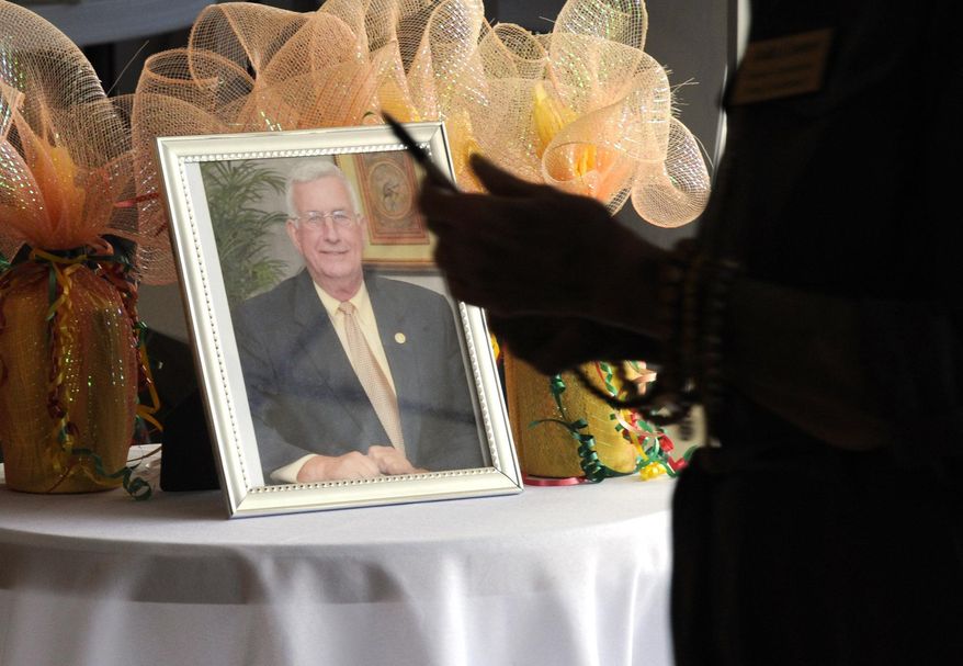 A person entering a memorial service for Mayor Billy Joe Driver in Clanton, Ala., walks past a photo of the longtime public official on Friday, Aug. 28, 2020. Driver's death of COVID-19 shocked the central Alabama community, where residents say many people thought the illness caused by the new coronavirus was a big-city problem until he succumbed. (AP Photo/Jay Reeves)