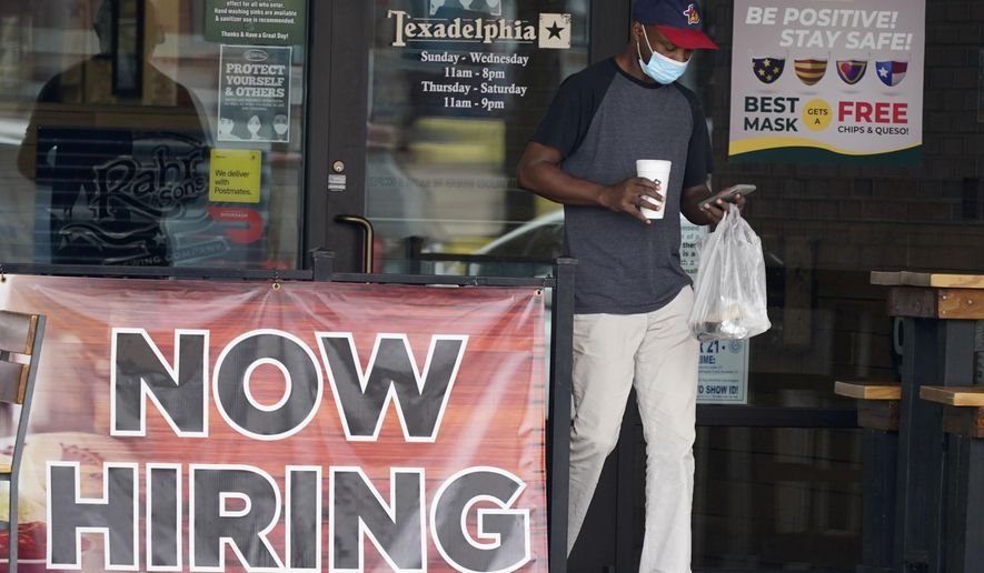 A customer wears a mask and looks at their cell phone as they carry their order past a now hiring sign at an eatery in Richardson, Texas, Wednesday, Sept. 2, 2020. The U.S. unemployment rate fell sharply in August to 8.4%  from 10.2% even as hiring slowed in August as employers added the fewest jobs since the pandemic began. (AP Photo/LM Otero)