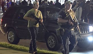 In this Aug. 25, 2020, file photo, Kyle Rittenhouse, left, with backwards cap, walks along Sheridan Road in Kenosha, Wis., with another armed civilian. (Adam Rogan/The Journal Times via AP, File)