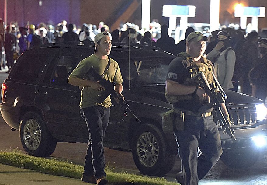 In this Aug. 25, 2020, file photo, Kyle Rittenhouse, left, with backwards cap, walks along Sheridan Road in Kenosha, Wis., with another armed civilian. (Adam Rogan/The Journal Times via AP, File)