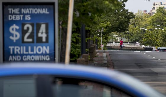 In this April 29, 2020 file photo, a sign displaying the size of the national debt is displayed along an empty K Street in Washington. The Congressional Budget Office has warned that the government this year will run the largest budget deficit, as a share of the economy, since 1945, the year World War II ended. Next year, the federal debt — made up of the year-after-year gush of annual deficits — is forecast to exceed the size of the entire American economy for the first time since 1946. (AP Photo/Andrew Harnik, File)