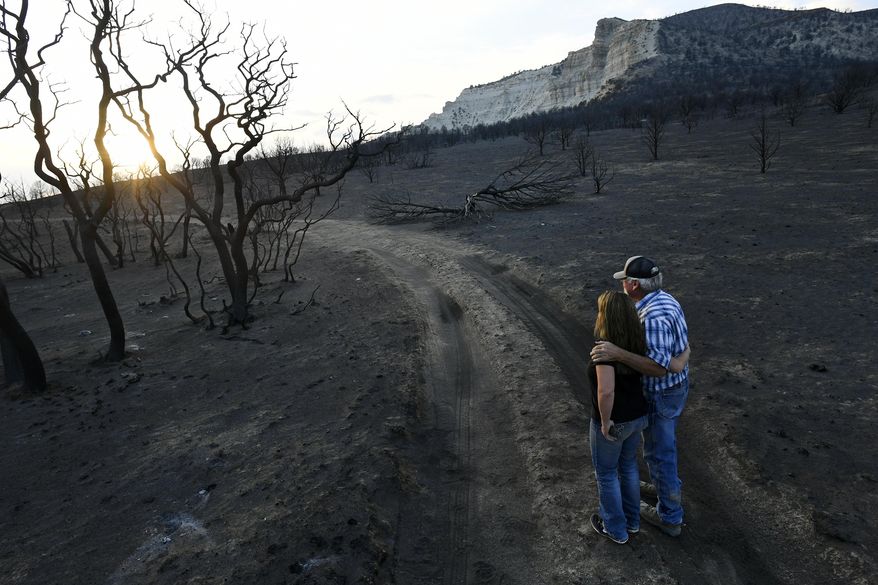 Amy Latham Largent, left, and her dad Dick Latham, share a quiet moment of reflection as they survey the damage to her family's land from the Pine Gulch Fire on Aug. 27, 2020, near De Beque, Colorado. The fire burned the land so quickly and badly that in many parts nothing is left but deep ash, soot and stumps of trees and brush that had been there before. (Helen H. Richardson/The Denver Post via AP)