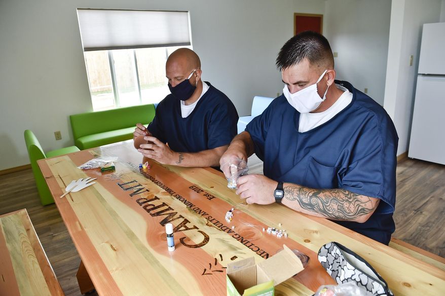 Incarcerated fathers Jeramie Carr, right, and Jesse Harrison work on a crafting activity at the Montana State Prison in Deer Lodge, Mont. The prison is offering a program called Connecting Adults and Minors through Positive Parenting, or CAMPP, intended to help incarcerated fathers connect with their children so they can be better parents when they are released from prison. Due to COVID-19 restrictions, the in-person activities have gone virtual. (Thom Bridge/Independent Record via AP)