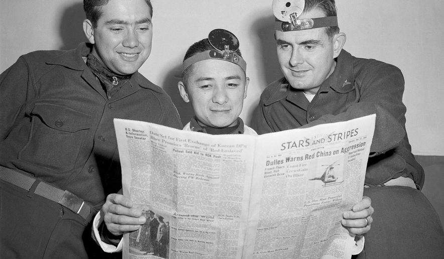 Former Olympic diver Sammy Lee, with co-workers at the hospital in Seoul, Korea, read the news of his award in the Stars and Stripes, Dec. 1953. From left: Cpl. Homer R. Banham of Paris, Mo.; Lee; and Capt. Jules A Howell of Winston-Salem, N.C. (AP Photo/George Sweers) ** FILE **