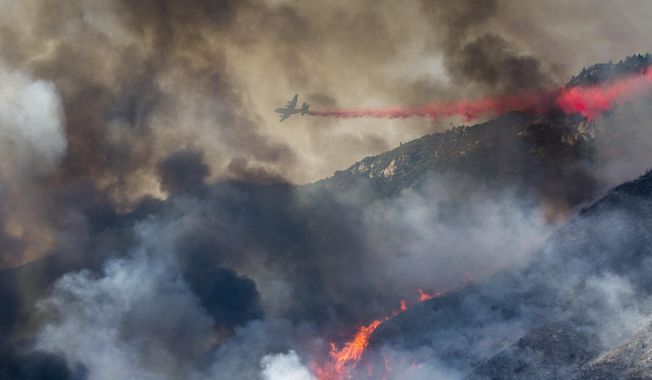 An air tanker drops retardant at a wildfire burns at a hillside in Yucaipa, Calif., Saturday, Sept. 5, 2020. Three fast-spreading wildfires sent people fleeing and trapped campers in one campground as a brutal heat wave pushed temperatures above 100 degrees in many parts of California. (AP Photo/Ringo H.W. Chiu)