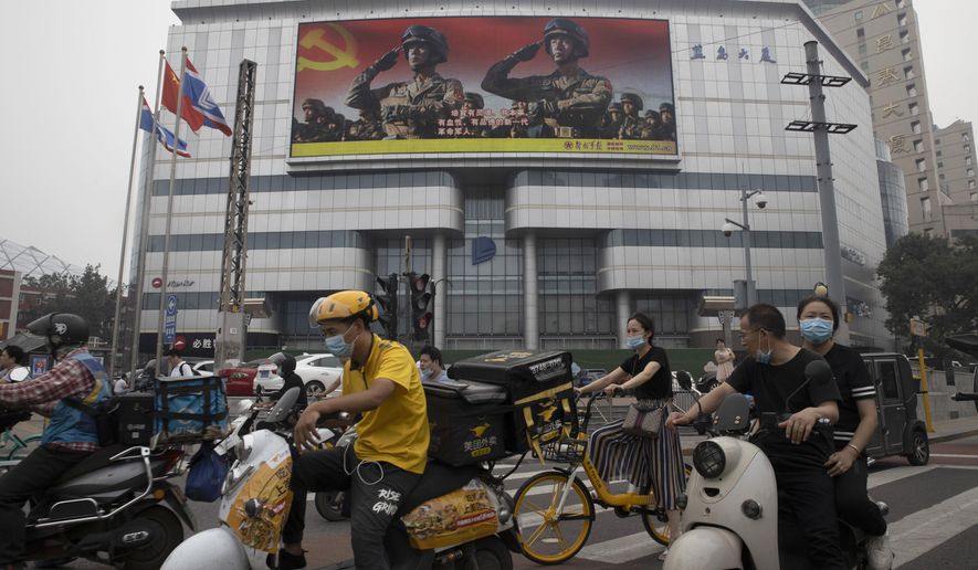 Residents wearing mask to protect themselves from  contracting the coronavirus pass by a Chinese military propaganda display in Beijing on Wednesday, Aug. 26, 2020. China is protesting the alleged incursion of a U.S. Air Force U-2 spy plane into a no-fly zone imposed during live-fire military exercises in the country&#39;s north in a statement issued Tuesday, Aug 25, 2020. (AP Photo/Ng Han Guan)