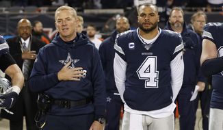 FILE - In this Dec. 5, 2019, file photo, Dallas Cowboys coach Jason Garrett and quarterback Dak Prescott (4) listen to the national anthem before the team&#39;s NFL football game against the Chicago Bears in Chicago.  Prescott wants his teammates to decide for themselves whether to protest during the national anthem. Defensive lineman Tyrone Crawford says they have the “green light” to do so. Owner Jerry Jones hasn&#39;t said in so many words, but it appears his hard-line stance over his players standing during the anthem has eased amid a national reckoning over racial justice. (AP Photo/Charles Rex Arbogast, File)