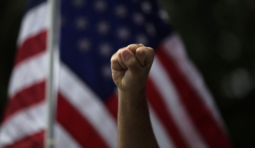 FILE - In this June 1, 2020, file photo a demonstrator raises his fist during a protest over the death of George Floyd, in Anaheim, Calif. The three month stretch between the symbolic kickoff and close of America’s summer has both galvanized broad public support for the racial justice movement and exposed the obstacles to turning that support into concrete political and policy changes. (AP Photo/Jae C. Hong, File)