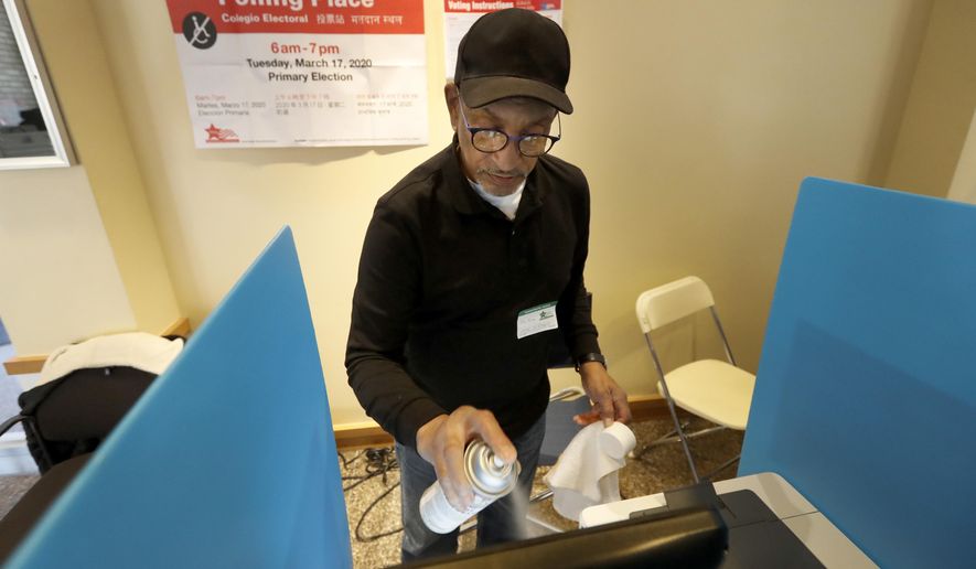 FILE - In this March 17, 2020 file photo, John Davis, a polling judge volunteer, sanitizes an electronic voting machine screen amid concerns about the COVID-19 coronavirus at a polling place in Chicago. More than 1 million Illinoisans have applied to vote by mail for the November election, nearly triple the amount of the last presidential contest. The surge comes after an expansion of mail voting designed to limit Election Day crowds during the pandemic. (AP Photo/Charles Rex Arbogast File)