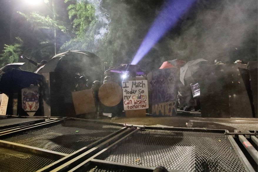 Demonstrators in Portland, Oregon, use shields to protect themselves from police wielding tear gas canisters. A strange armed conflict unfolds night after night. It is raw, frightening and painful on both sides. (Associated Press)