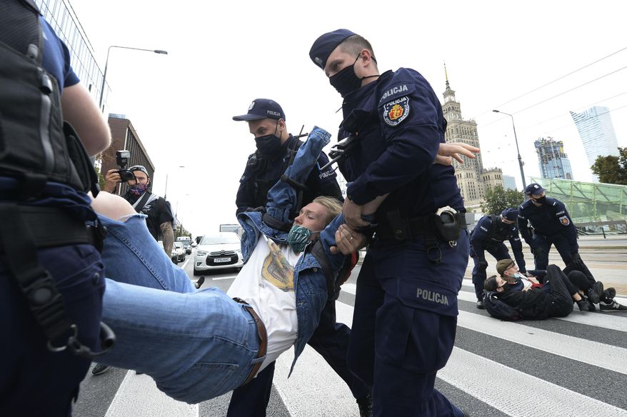 Polish police carry protesting environmentalists to the side to clear passage down one of Warsaw's main streets in Warsaw, Poland, Monday, Sept. 7, 2020. The Polish chapter of the international environmental group Extinction Rebellion blocked the street to spur the government into better protection of the environment, in a second such action in two days, in Warsaw. (AP Photo/Czarek Sokolowski)