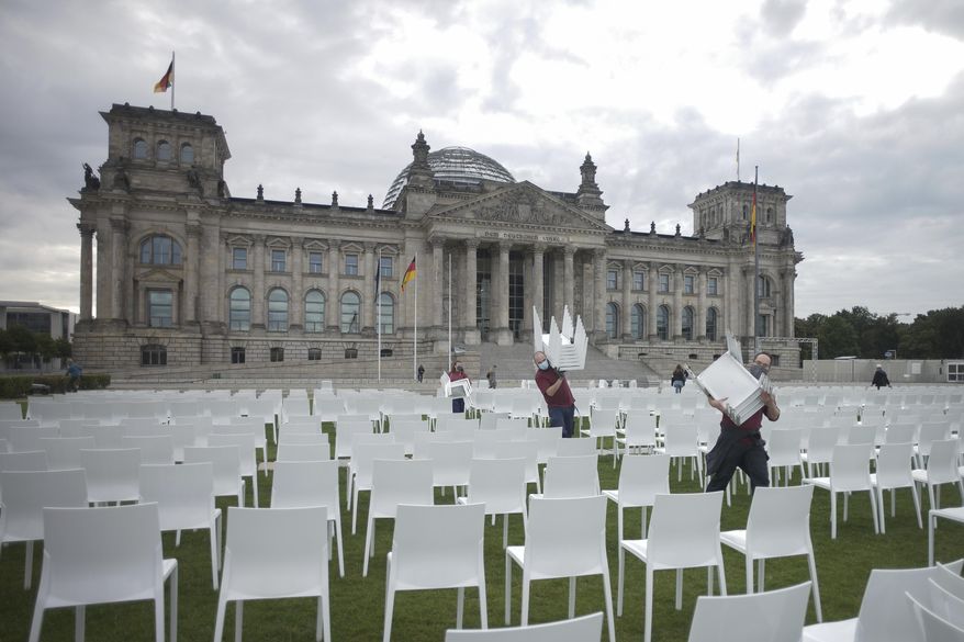 Activists place chairs as part of a protest against racism and for the admission of more migrants by the European Union in front of the Reichstags building in Berlin, Germany, Monday, Sept. 7, 2020. (AP Photo/Markus Schreiber)