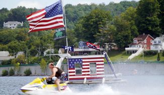 A jet skier passes a patriotic shanty-boat owned by AJ Crea on Pontoosuc Lake on Labor Day in Pittsfield, Mass., Monday, Sept. 7, 2020. (Ben Garver/The Berkshire Eagle via AP)