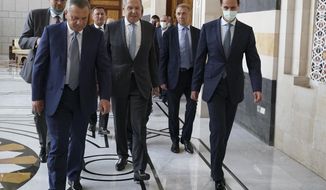 In this photo released on the official Facebook page of the Syrian Presidency, shows Syrian President Bashar Assad, right, wearing a mask to help prevent the spread of the coronavirus, walks with Russian Foreign Minister Sergey Lavrov, center, and Deputy Prime Minister Yuri Borisov, left, in Damascus, Syria, Monday, Sept. 7, 2020.  Lavrov met with Syrian President Bashar Assad shortly after landing in the Syrian capital on his first visit since 2012. (Syrian Presidency via Facebook)