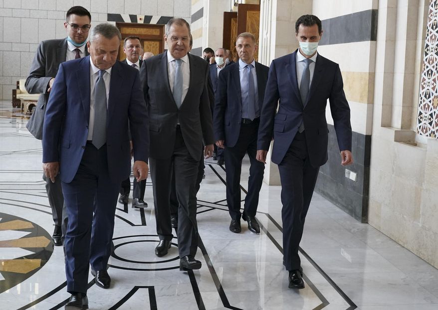 In this photo released on the official Facebook page of the Syrian Presidency, shows Syrian President Bashar Assad, right, wearing a mask to help prevent the spread of the coronavirus, walks with Russian Foreign Minister Sergey Lavrov, center, and Deputy Prime Minister Yuri Borisov, left, in Damascus, Syria, Monday, Sept. 7, 2020.  Lavrov met with Syrian President Bashar Assad shortly after landing in the Syrian capital on his first visit since 2012. (Syrian Presidency via Facebook)