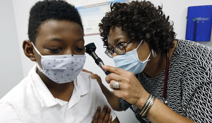 Dr. Janice Bacon, a primary care physician with Central Mississippi Health Services, gives Jeremiah Young, 11, a back-to-school physical, at the Community Health Care Center on the Tougaloo College campus, in Tougaloo, Miss., on Aug. 14, 2020. As a Black primary care physician, Bacon has created a safe space for her Black patients during the coronavirus pandemic. (AP Photo/Rogelio V. Solis)