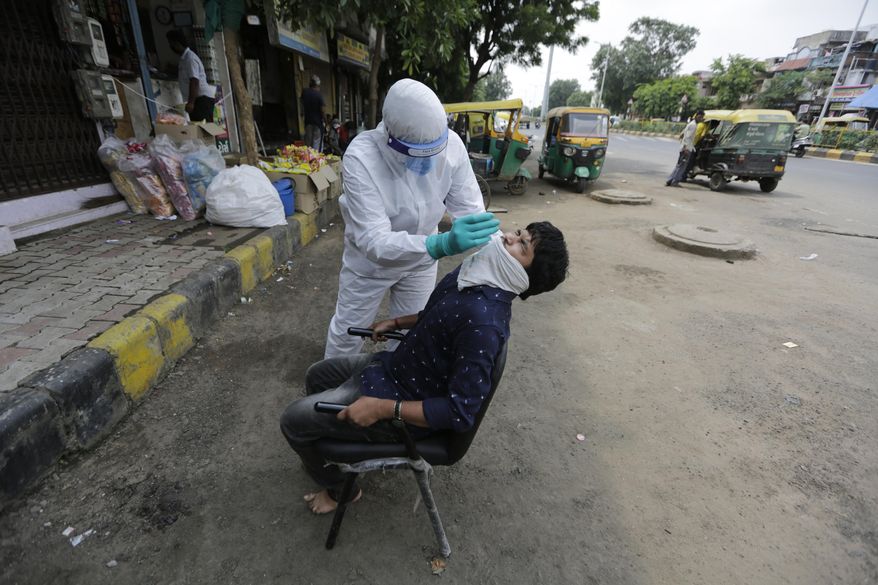 A health worker takes a nasal swab sample to test for COVID-19 in Ahmedabad, India, Tuesday, Sept. 8, 2020. India's coronavirus cases are now the second-highest in the world and only behind the United States. (AP Photo/Ajit Solanki)