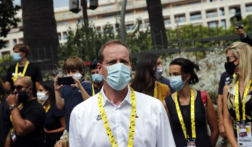FILE- In this Aug. 29, 2020, file photo Tour de France director Christian Prudhomme, center, wears a face mask as he attends the start of the first stage of the Tour de France cycling race in Nice, southern France, Saturday, Aug. 29, 2020. Organizers announced that Prudhomme tested positive after taking a COVID-19 test, without providing further details. (AP Photo/Christophe Ena, File)