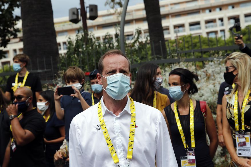 FILE- In this Aug. 29, 2020, file photo Tour de France director Christian Prudhomme, center, wears a face mask as he attends the start of the first stage of the Tour de France cycling race in Nice, southern France, Saturday, Aug. 29, 2020. Organizers announced that Prudhomme tested positive after taking a COVID-19 test, without providing further details. (AP Photo/Christophe Ena, File)