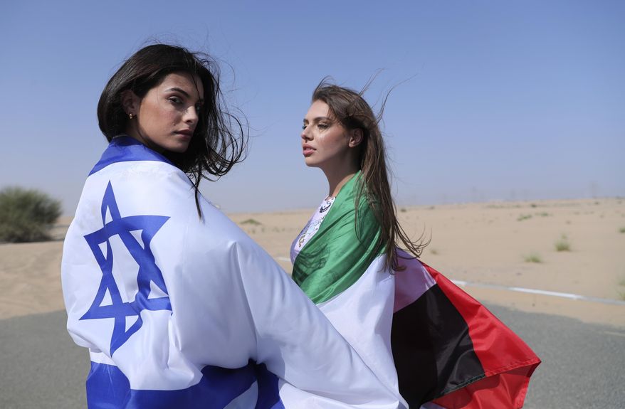 Israeli model May Tager, left, covers herself with an Israeli flag next to Anastasia Bandarenka, a Dubai-based model who covers herself in a UAE flag on the set of a photo shoot in Dubai, United Arab Emirates, Sunday, Sept. 8, 2020. (AP Photo/Kamran Jebreili)