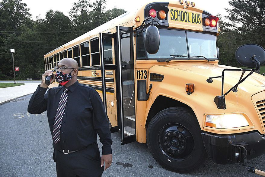 Beckley Stratton Middle School principal Yahon Smith monitors school buses and parent drop off of students for the first day of school Tuesday morning, Sept. 8, 2020, in Beckley, W.Va. (Rick Barbero/The Register-Herald via AP)