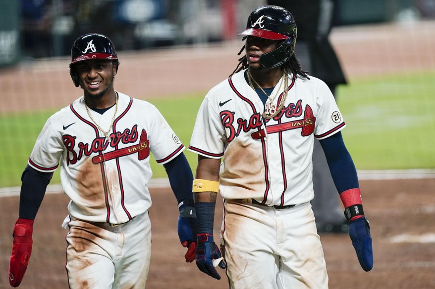 Atlanta Braves' Ozzie Albies, left and Ronald Acuna Jr. walk to dugout after scoring during the fourth inning the team's a baseball game against the Miami Marlins Wednesday, Sept. 9, 2020, in Atlanta. (AP Photo/Brynn Anderson)