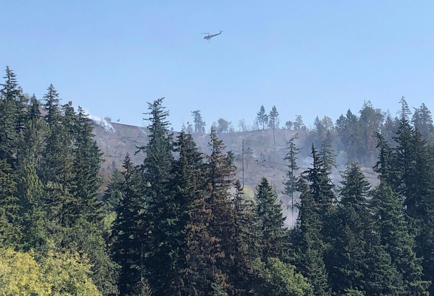 A helicopter flies over fires burning on a ridge in Sumner, Wash., Wednesday, Sept. 9, 2020. Windblown wildfires raging across the Pacific Northwest destroyed hundreds of homes in Oregon, the governor said Wednesday, warning: "This could be the greatest loss of human life and property due to wildfire in our state's history." (AP Photo/Rachel La Corte)