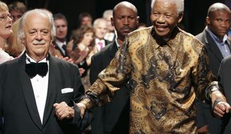 FILE — In this Wednesday Nov. 12, 2008 file photo George Bizos, left, anti-apartheid activist, and life-long friend and lawyer of Nelson Mandela, right, arrives for his 80th birthday party in Johannesburg, South Africa. Bizos has died Wednesday Sept. Sept. 9, 2020, aged 92. (AP Photo/Denis Farrell)