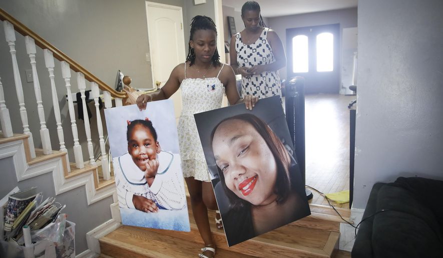 Eryanna Banks, left, carries photos of her Aunt Lydia Nunez, who died from COVID-19, in front of her mother Erika at the end of the day following a memorial service and burial for Nunez Tuesday, July 21, 2020, in Los Angeles. (AP Photo/Marcio Jose Sanchez)