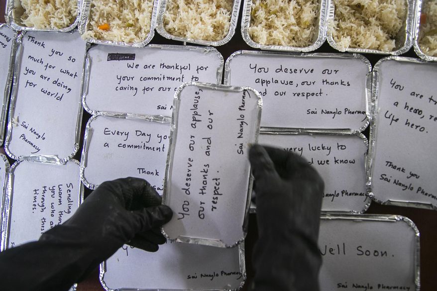 A Volunteer packs food for doctors and COVID-19 patients in Kathmandu, Nepal, Tuesday, Sept. 1, 2020. At one of the largest hospitals in Nepal, a pharmacist and taxi driver have teamed up to feed COVID-19 patients, doctors, nurses and health workers. Due to lockdowns, the cafeteria and nearby cafes have closed, leaving more than 200 staffers, patients and their families without food. The two friends have taken their own money and donations and put it to use buying groceries, renting a kitchen and paying helpers to provide the meals. (AP Photo/Niranjan Shrestha)