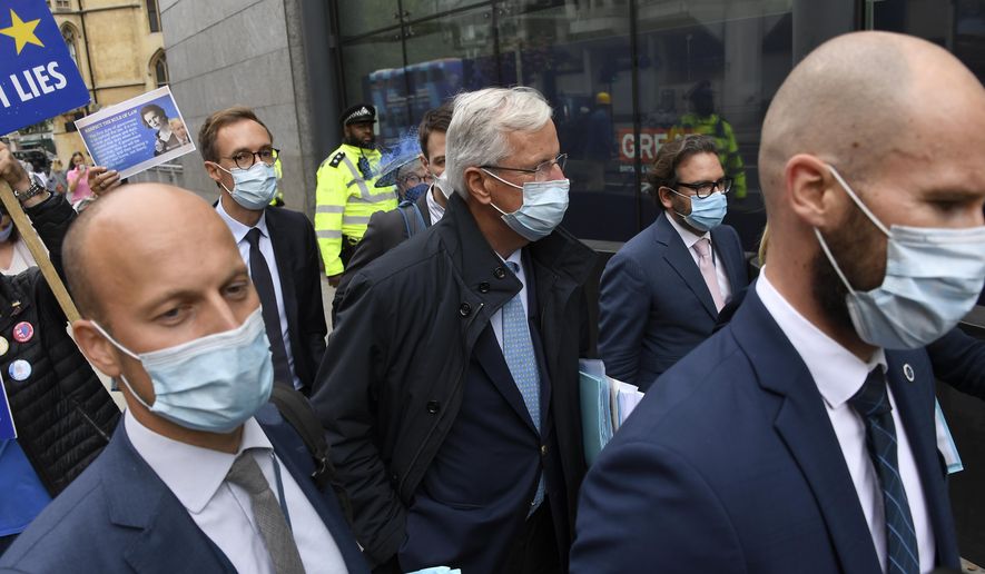 EU Chief negotiator Michel Barnier, center, is surrounded by delegates and pro-EU protesters as he arrives at the Westminster Conference Centre in London, Wednesday, Sept. 9, 2020. U.K. and EU officials begin the eighth round of Brexit negotiations in London. (AP Photo/Alberto Pezzali)
