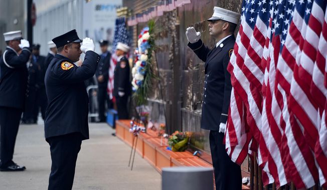 New York City firefighters salute in front of a memorial on the side of a firehouse adjacent to One World Trade Center and the 9/11 Memorial site during ceremonies on the anniversary of 9/11 terrorist attacks in New York, Sept. 11, 2018. (AP Photo/Craig Ruttle, File)