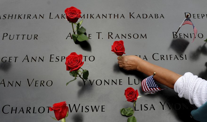 FILE - In this Sept. 11, 2014, file photo, a woman places flowers in the inscribed names along the edge of the North Pool during memorial observances on the 13th anniversary of the Sept. 11, 2001 terror attacks on the World Trade Center in New York. The coronavirus pandemic has reshaped how the U.S. is observing the anniversary of 9/11. The terror attacks' 19th anniversary will be marked Friday, Sept. 11, 2020, by dueling ceremonies at the Sept. 11 memorial plaza and a corner nearby in New York. (AP Photo/Justin Lane, Pool, File)