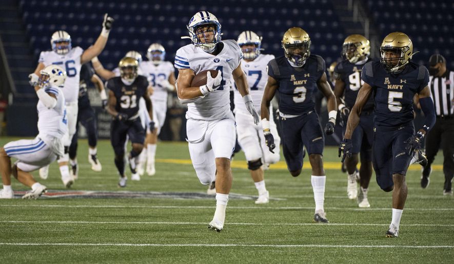 FILE - In this Monday, Sept. 7, 2020 file photo, BYU running back Lopini Katoa runs for a touchdown as Navy cornerback Michael McMorris (5) and defensive back Cameron Kinley (3) chases during the first half of an NCAA college football game in Annapolis, Md. (AP Photo/Tommy Gilligan, File)