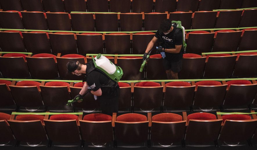 Two Zoono employees spray disinfectant on theater seats in the Wagner Noel Performing Arts Center on Thursday, Sept. 10, 2020, in Odessa, Texas, in preparation for the reopening of the venue for its first performance on Sept. 15. (Eli Hartman/Odessa American via AP)