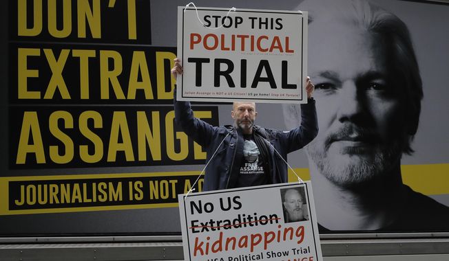 A demonstrator holds placards near the Central Criminal Court Old Bailey in London, Tuesday, Sept. 8, 2020. Lawyers for WikiLeaks founder Julian Assange and the U.S. government were squaring off in a London court on Monday at a high-stakes extradition case delayed by the coronavirus pandemic. American prosecutors have indicted the 49-year-old Australian on 18 espionage and computer misuse charges over Wikileaks&#x27; publication of secret U.S. military documents a decade ago. The charges carry a maximum sentence of 175 years in prison. (AP Photo/Kirsty Wigglesworth)