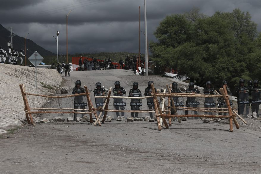National Guard troops equipped with riot gear stand guard at Las Pilas dam, two days after withdrawing from nearby La Boquilla dam after clashing with hundreds of farmers, in Camargo, Chihuahua State, Mexico, Thursday, Sept. 10, 2020. President Andrés Manuel López Obrador said Thursday he regretted the killing of a woman and the wounding of her husband following a Tuesday clash between National Guard troops and farmers over water. (AP Photo Christian Chavez)