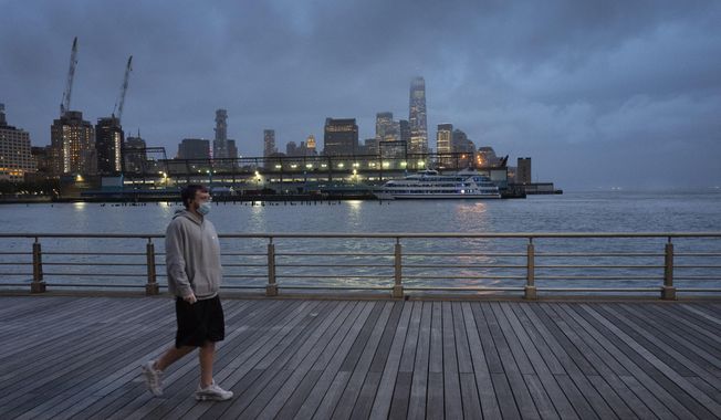 In this April 30, 2020, photo, a man wears a face mask as he walks on Pier 45 in Hudson River Park in New York. The coronavirus pandemic has taken a harsh toll on the mental health of young Americans, according to a new poll that finds adults under 35 especially likely to report negative feelings or experience physical or emotional symptoms associated with stress and anxiety. (AP Photo/Mark Lennihan) **FILE**