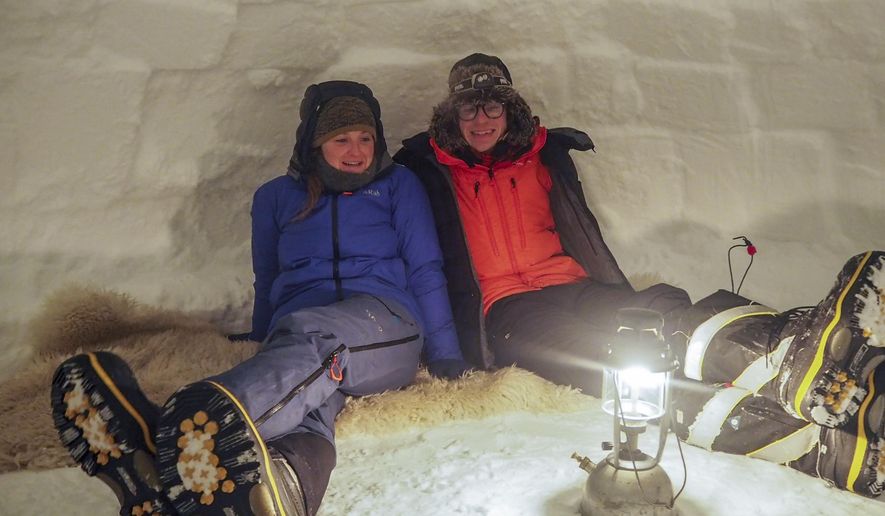 In this handout photo provided by British Antarctic Survey, field guide Sasha Doyle, left, and meteorological observer Jack Farr, right, sit in an igloo in Trident area, Adelaide island, in Antarctica in October 2019. Antarctica remains the only continent without COVID-19 and now in Sept. 2020, as nearly 1,000 scientists and others who wintered over on the ice are seeing the sun for the first time in months, a global effort wants to make sure incoming colleagues don&#39;t bring the virus with them. (Robert Taylor/British Antarctic Survey via AP)