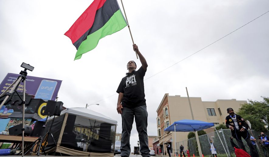 Duncan Ellington waves an African flag during a protest rally for Jacob Blake near Martin Luther King Park on West Vliet Street in Milwaukee, Saturday, Sept. 12, 2020. Blake was shot by police on Aug. 23 as he was being arrested in Kenosha, Wis. (Mike De Sisti/Milwaukee Journal-Sentinel via AP)