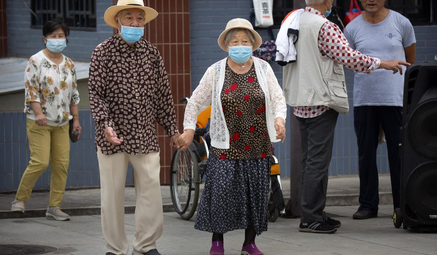 An elderly couple wearing face masks to protect against the coronavirus walks at a public park in Beijing, Saturday, Sept. 12, 2020. Even as China has largely controlled the outbreak, the coronavirus is still surging across other parts of the world. (AP Photo/Mark Schiefelbein)