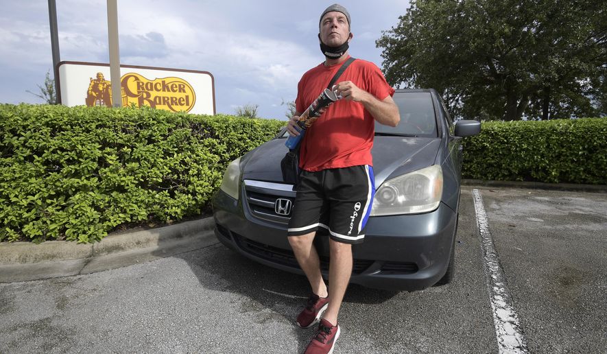Jeff Lello stands in front of the van in which he lives, in the parking lot of a Cracker Barrel restaurant, since being laid off due to the coronavirus pandemic, Friday, Aug. 21, 2020, in Orlando, Fla. Lello is one of an estimated 20 million Americans living paycheck to paycheck, spending more than 30% of their income on rent, who are likely to experience homelessness at some point, according to the National Coalition for the Homeless. (AP Photo/Phelan M. Ebenhack)