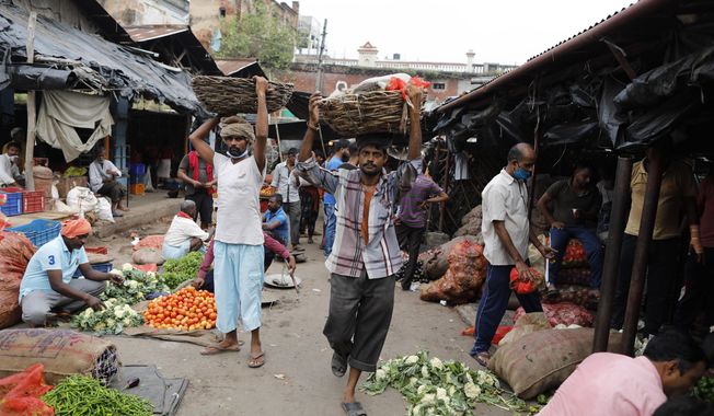 Laborers carry vegetables early morning at a wholesale market in Lucknow, India, Saturday, Sept. 12, 2020. Millions lost their jobs, and thousands, fearing starvation, poured out of cities to try and get back to their rural homes during India’s lockdown of 1.3 billion people earlier this year. The economy shrunk by nearly 24% in the last quarter, the most of any major country. (AP Photo/Rajesh Kumar Singh)