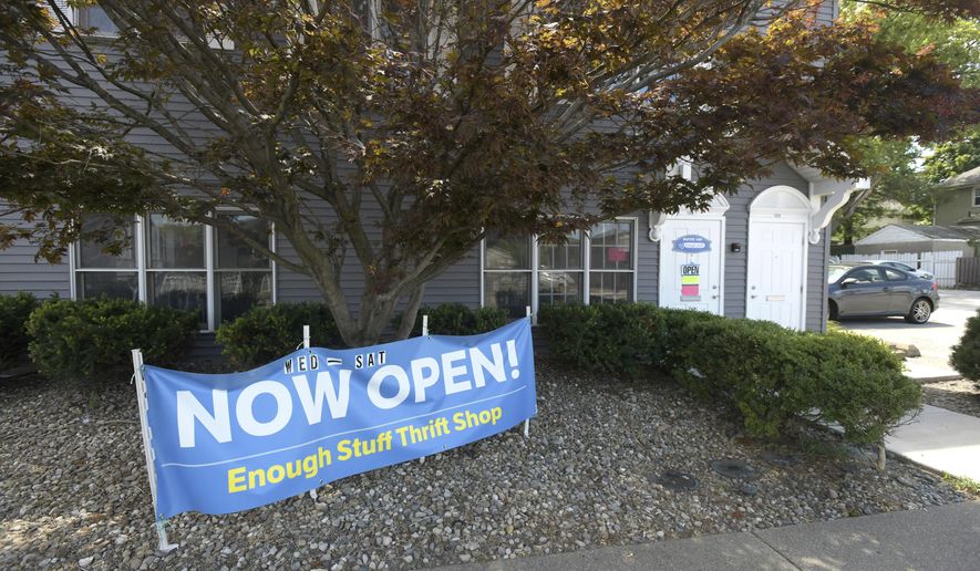 A sign announces the opening of Enough Stuff Thrift Shop & Community Space in East Peoria, Ill., on Aug. 19, 2020. Items at Enough Stuff Thrift Shop & Community Space are not priced. Instead, customers can take them for free, make a donation, or sign up to be a part of a monthly subscription service that supports the shop. (Leslie Renken/Journal Star via AP)