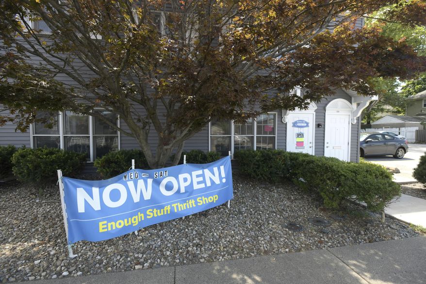A sign announces the opening of Enough Stuff Thrift Shop & Community Space in East Peoria, Ill., on Aug. 19, 2020. Items at Enough Stuff Thrift Shop & Community Space are not priced. Instead, customers can take them for free, make a donation, or sign up to be a part of a monthly subscription service that supports the shop. (Leslie Renken/Journal Star via AP)