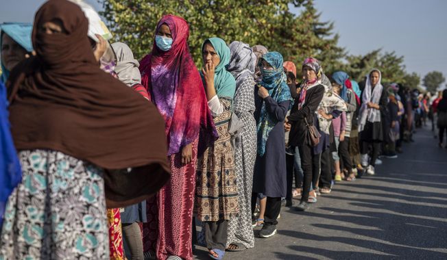 Migrants wait in a queue for food distribution near Mytilene town, on the northeastern island of Lesbos, Greece, Saturday, Sept. 12, 2020. Greek authorities have been scrambling to find a way to house more than 12,000 people left in need of emergency shelter on the island after the fires deliberately set on Tuesday and Wednesday night gutted the Moria refugee camp. (AP Photo/Petros Giannakouris)