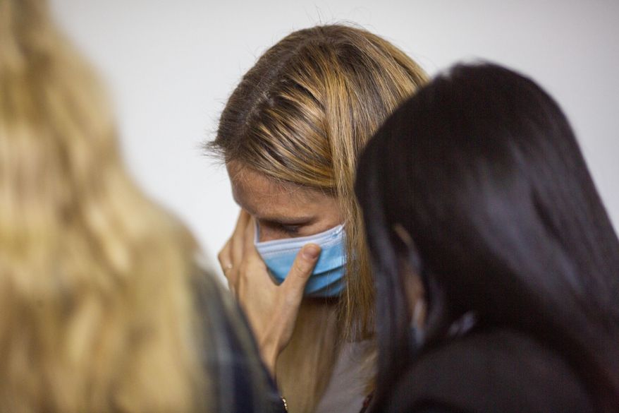 Israeli top model Bar Refaeli wears a face mask amid the coronavirus pandemic as she speaks to her lawyers inside a courtroom in Tel Aviv, Israel, Sunday, Sept. 13, 2020. The Israeli court sentenced top model Bar Refaeli to nine months of community service and her mother was sentenced to 16 months in prison, ending a prolonged tax evasion case that had sullied the image of a once beloved national icon. (AP Photo/Ariel Schalit, Pool)